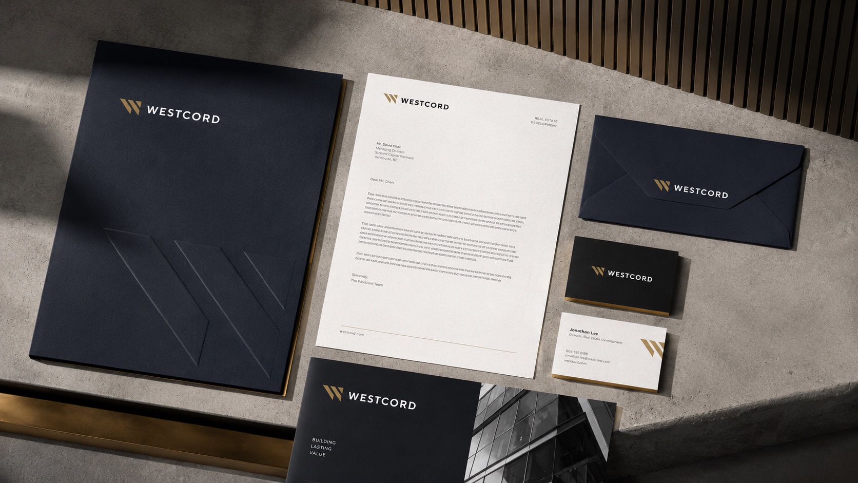 Westcord stationery flatlay with branded folder, letterhead, envelope and business cards arranged on a concrete surface.
